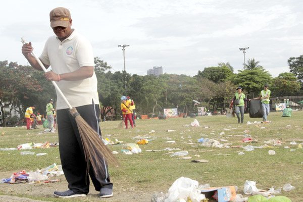 Workers from the Metropolitan Manila Development Authority clean up the mess that is the open field of Rizal Park on Monday, a day after the New Year’s Day celebration. PHOTO BY ROGER RAÑADA