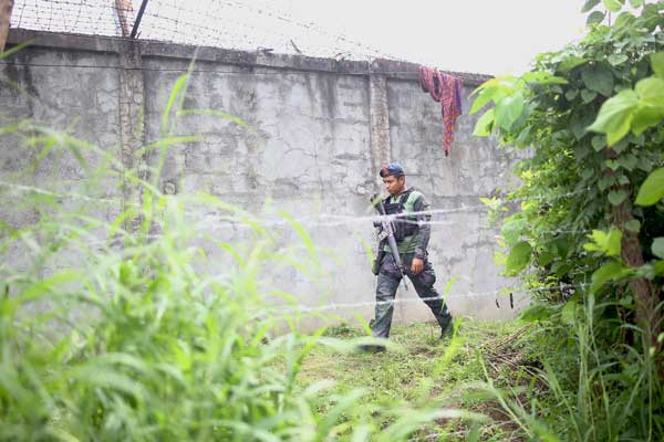 BUT THE BIRDS HAVE FLOWN An armed policeman patrols along the perimeter fence of the Kidapawan district jail hours after 158 inmates escaped. A jail guard was killed when dozens of armed rebels raided the facility. AFP PHOTO