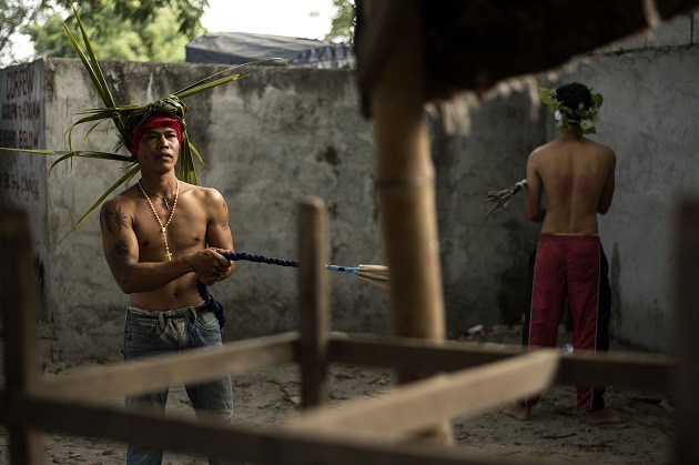 Flagellant RJ Rivera (L), whips his back with bamboo before being wounded to bleed as part of his penitence during the re-enactment of the crucifixion of Jesus Christ for Good Friday celebrations  in San Juan, Pampanga on March 30, 2018. 
